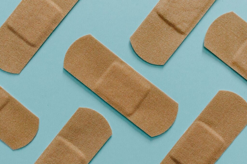 A minimalist flat lay of adhesive bandages on a blue background, perfect for health and treatment themes.