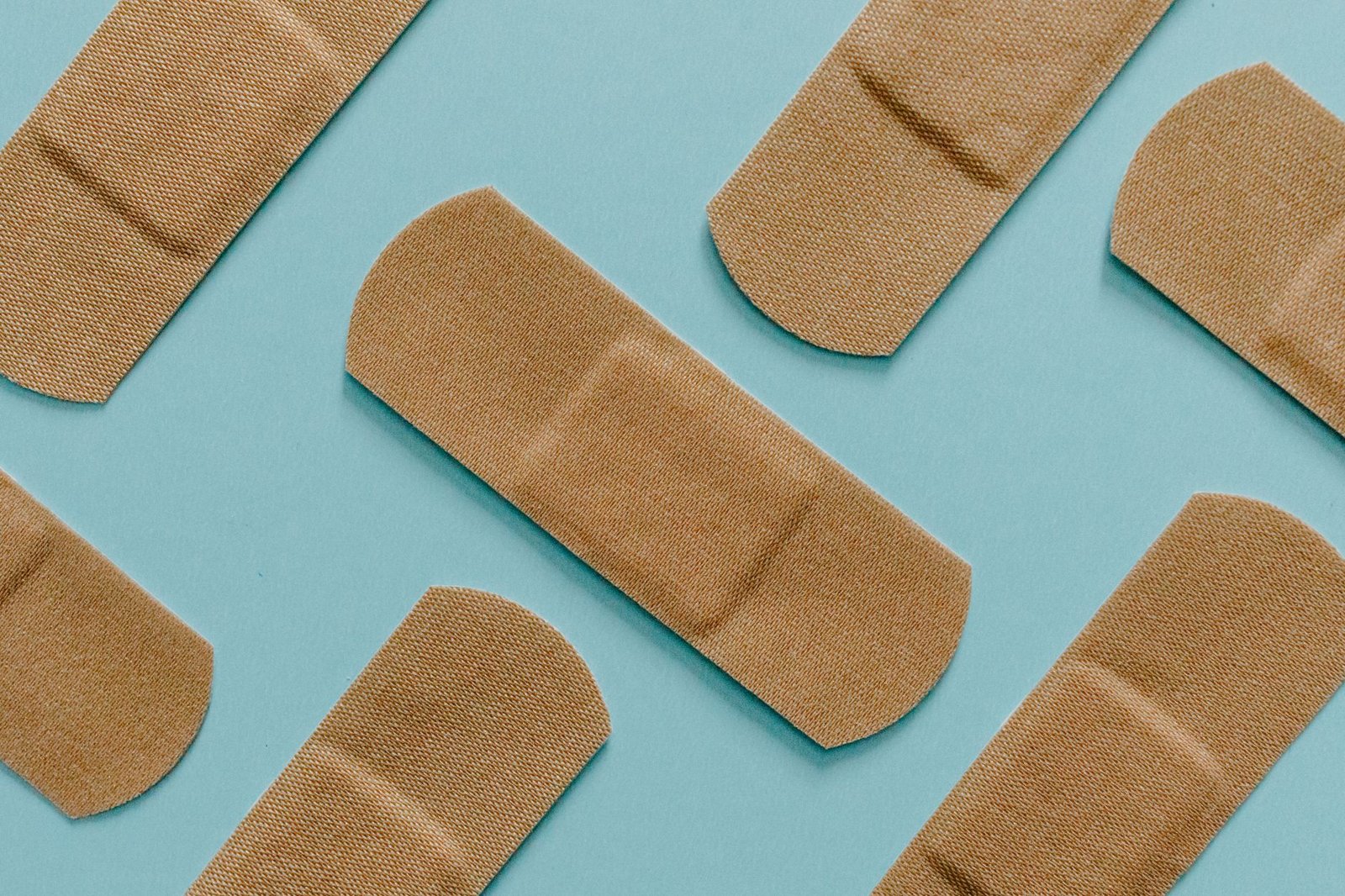 A minimalist flat lay of adhesive bandages on a blue background, perfect for health and treatment themes.