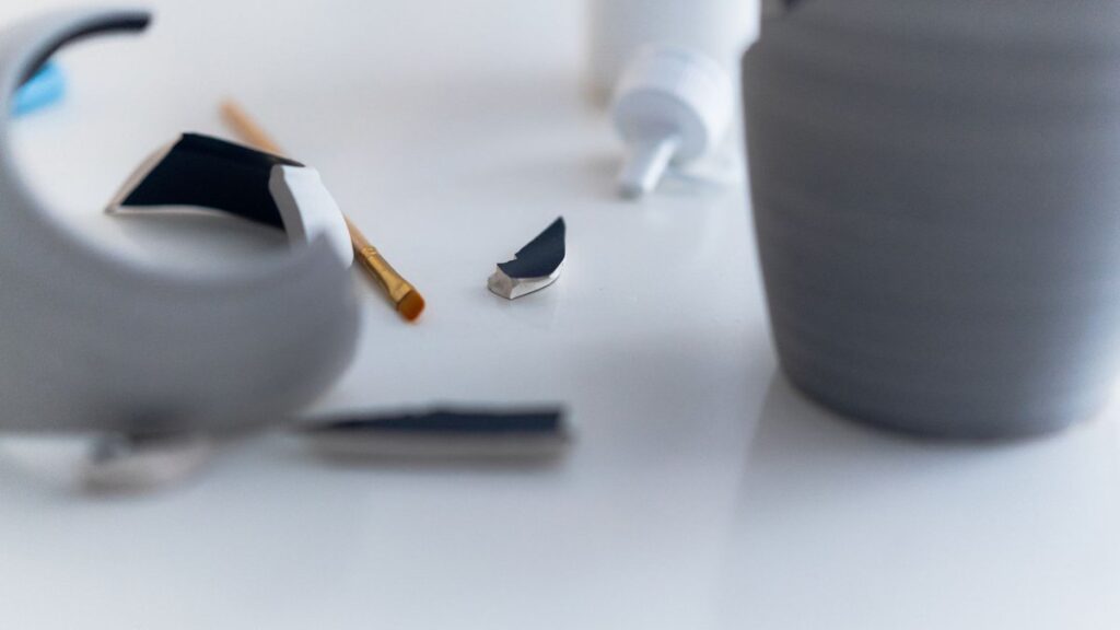 Close-up of a gray vase repair with glue and focus on broken pieces.