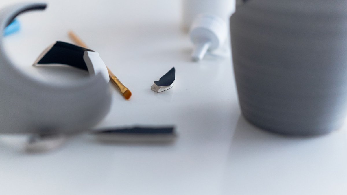 Close-up of a gray vase repair with glue and focus on broken pieces.