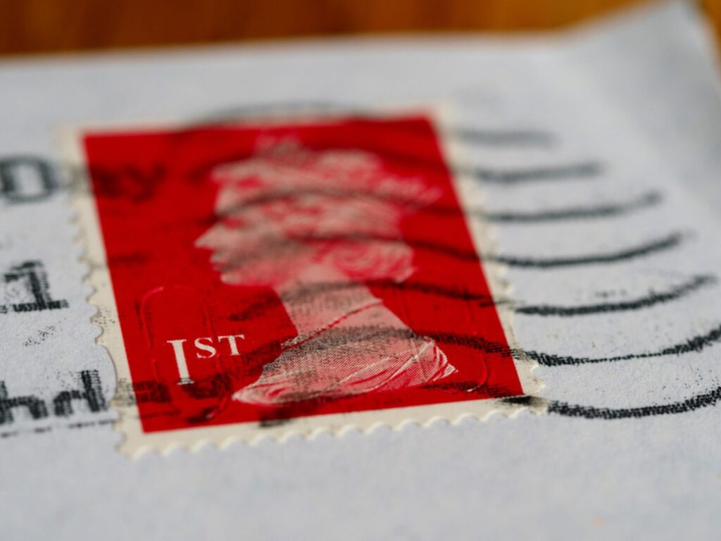 Detailed view of a red first-class postage stamp with a visible postmark.