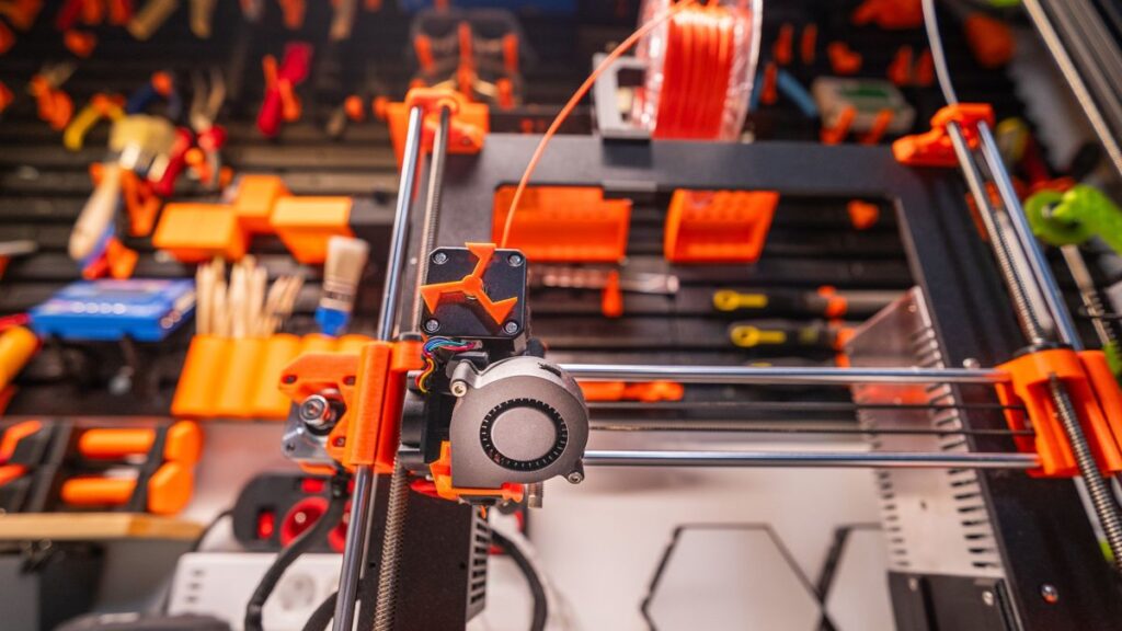 Detailed view of a 3D printer with filament and tools in a workshop setting.