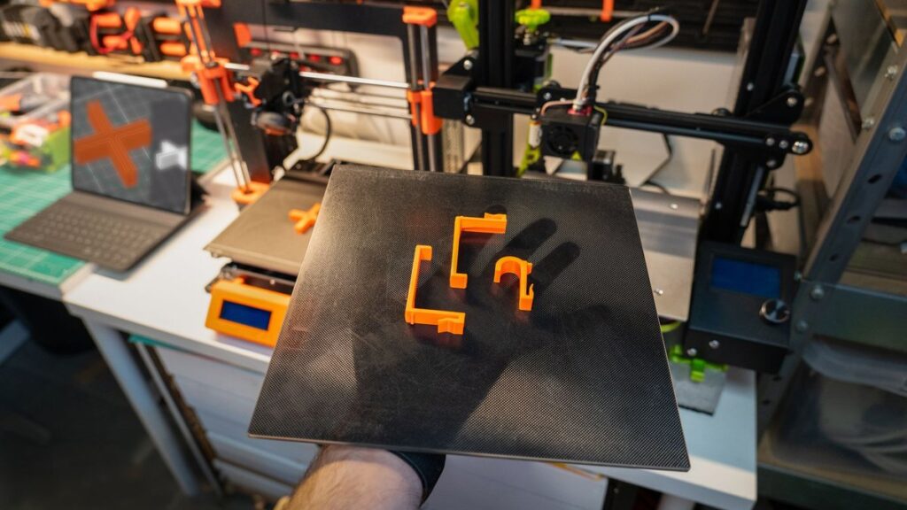 Close-up of a 3D printer and printed parts in a modern workshop setting.