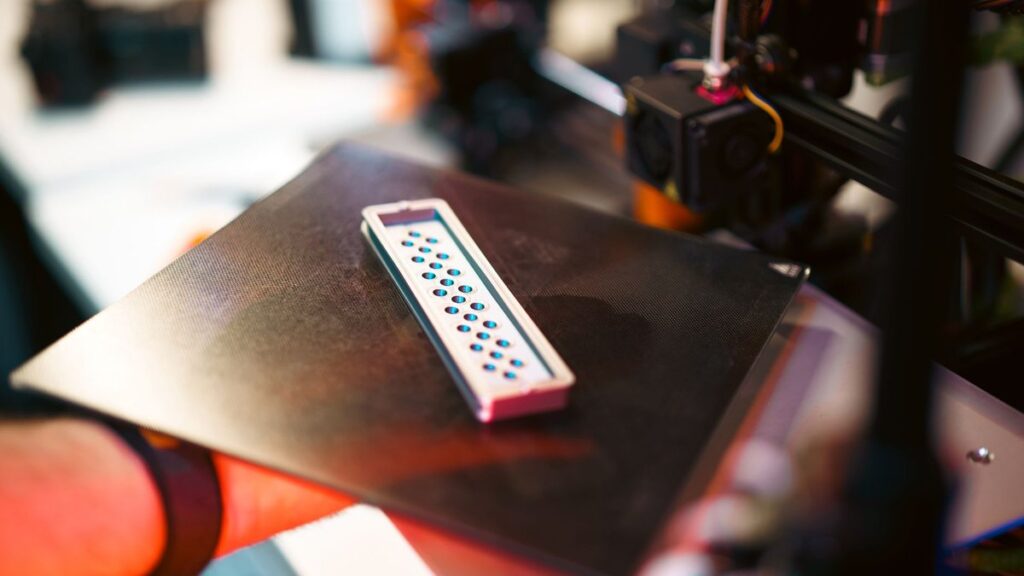 Close-up of a 3D printed part on an industrial printer in a workshop setting.