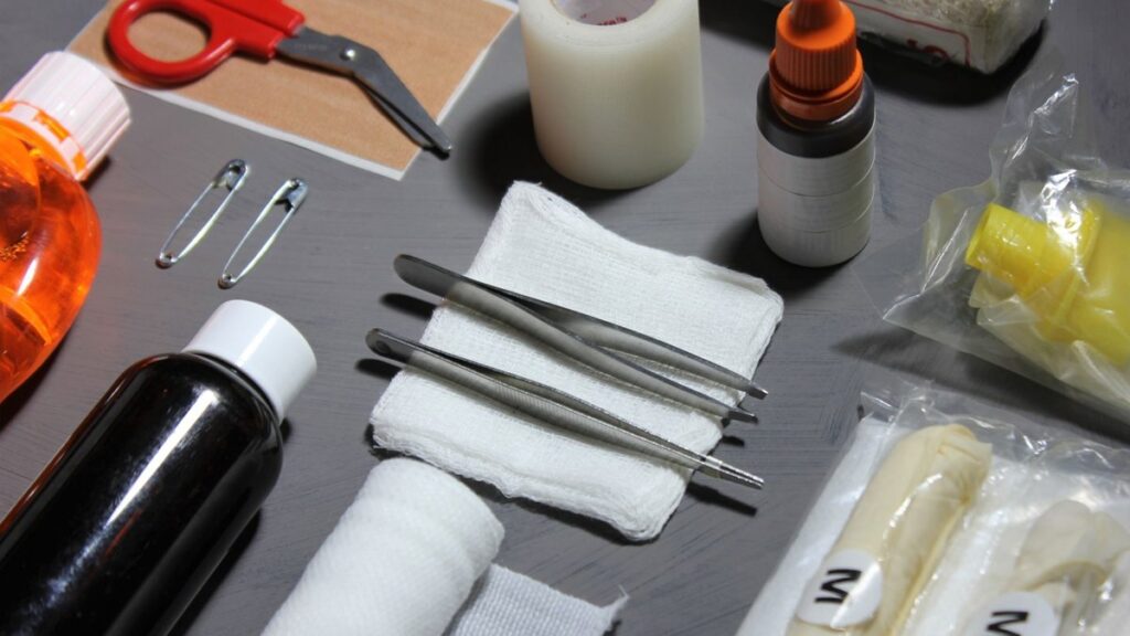 High-angle view of various essential first aid items, including bandages, gauze, scissors, and disinfectants on a table.