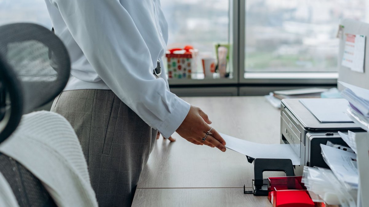 Business professional printing a document in an office environment.
