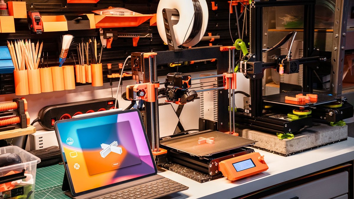 A high-tech workshop featuring 3D printers and a tablet on a desk, showcasing modern innovation.